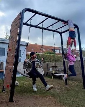 Newly assembled BERG PlayBase with a climbing wall, nest swing and swing seat in a customer's garden