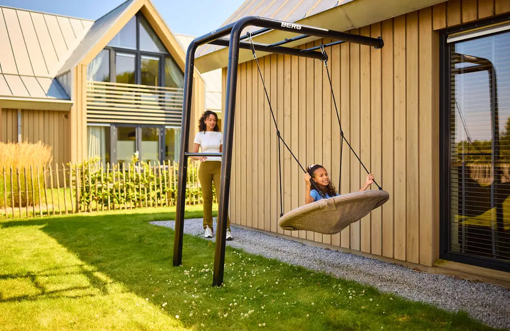 BERG PlayBase Wall climbing frame fixed to a house wall with a nest swing